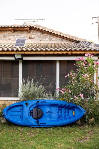 a blue kayak sitting on the grass in front of a house at Relaxing Stone Cottage in Aigio