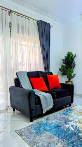 a black couch with red pillows in a living room at 2 Bedroom Spacious Kampala Buwate Stay A few Steps from the Mall in Buwate