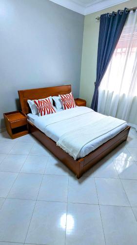 a bed sitting in a bedroom with a window at 2 Bedroom Spacious Kampala Buwate Stay A few Steps from the Mall in Buwate