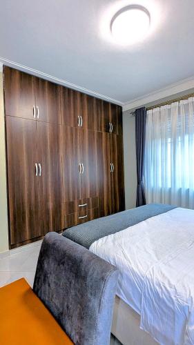 a bedroom with a bed and wooden cabinets at 2 Bedroom Spacious Kampala Buwate Stay A few Steps from the Mall in Buwate