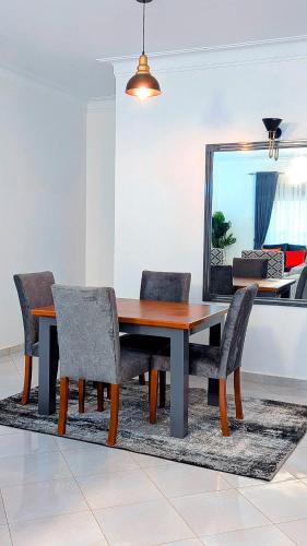 a dining room table with chairs and a mirror at 2 Bedroom Spacious Kampala Buwate Stay A few Steps from the Mall in Buwate