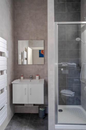 a bathroom with a white sink and a shower at Le Relais de l'Orangerie in Strasbourg