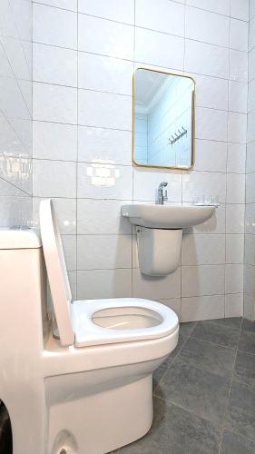 a bathroom with a toilet and a sink and a mirror at 2 Bedroom Spacious Kampala Buwate Stay A few Steps from the Mall in Buwate
