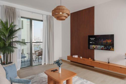 a living room with a couch and a tv on a wall at High-End Luxury 1BR in Port De La Mer near J1 Beachfront, Dubai in Dubai