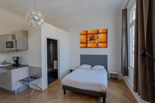 a bedroom with a white bed and a kitchen at Le Relais de l'Orangerie in Strasbourg