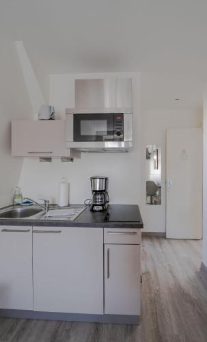 a white kitchen with a sink and a microwave at Le Relais de l'Orangerie in Strasbourg