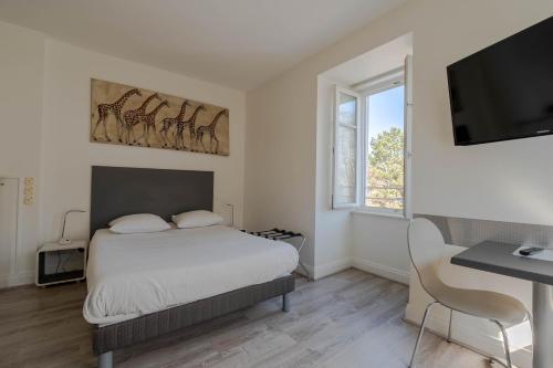a bedroom with a bed and a flat screen tv at Le Relais de l'Orangerie in Strasbourg