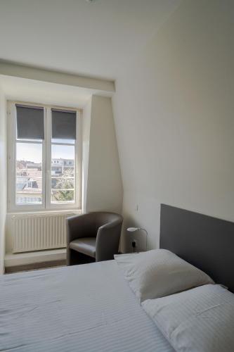 a bedroom with a bed and a chair and a window at Le Relais de l'Orangerie in Strasbourg