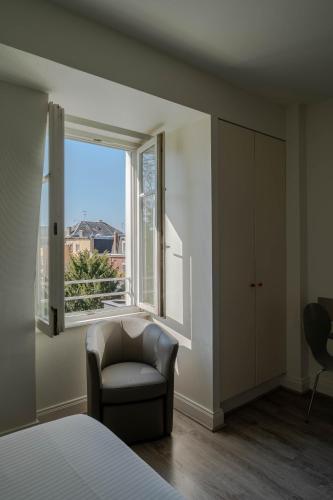 a bedroom with a chair and a large window at Le Relais de l'Orangerie in Strasbourg