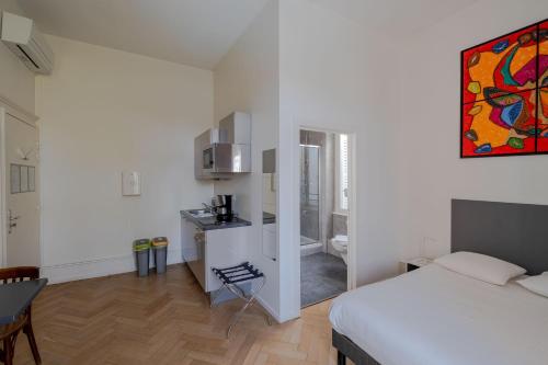 a bedroom with a bed and a kitchen with a table at Le Relais de l'Orangerie in Strasbourg