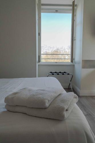 a bedroom with a bed with white sheets and a window at Le Relais de l'Orangerie in Strasbourg