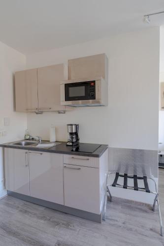a white kitchen with a sink and a microwave at Le Relais de l'Orangerie in Strasbourg