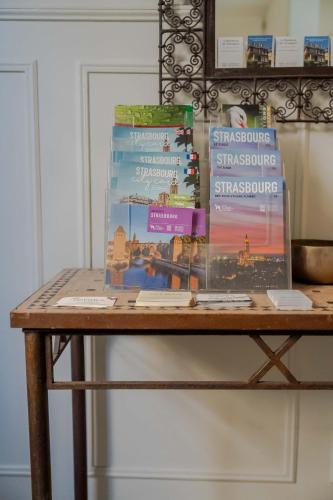 a table with three books on top of it at Le Relais de l'Orangerie in Strasbourg