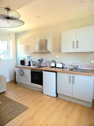 une cuisine avec des armoires blanches et un plancher en bois dans l'établissement Les Bons Enfants 5 & 8, à Rouen