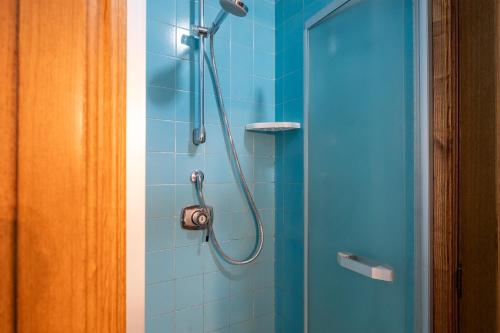a shower with a hose in a blue bathroom at Pool and Relax at Casa Ilenia in Bordighera