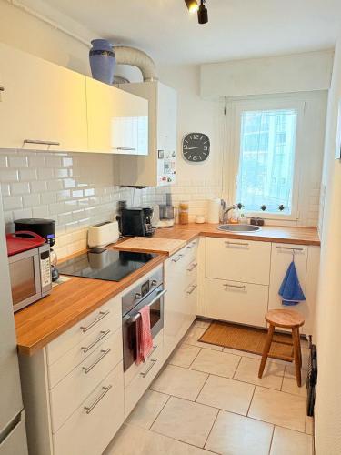 une cuisine avec des armoires blanches et un évier dans l'établissement Joli T2, classé 3 étoiles, climatisé vue mer, parking, à Sète