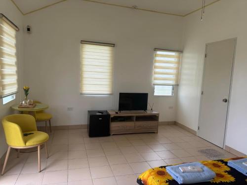 a living room with a tv and a yellow chair at Galaxy Villa Room in Dalaguete