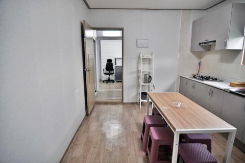 a kitchen with a table and purple chairs at Cozy Home at Gangneung Central Market in Gangneung
