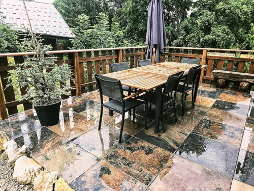 une table et des chaises en bois sur une terrasse avec un parasol dans l'établissement LatipiK - Chalet à La Plagne, à La Plagne Tarentaise