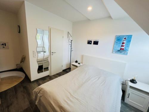 Un dormitorio blanco con una cama y un espejo. en kleines Strandhus, en Scharbeutz