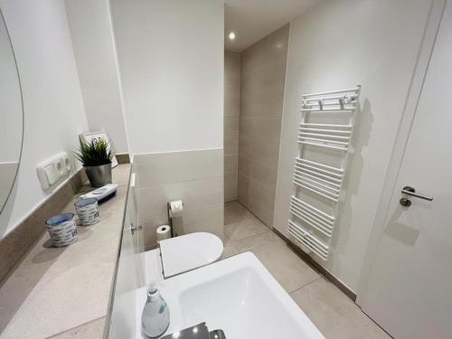 a white bathroom with a toilet and a sink at OceanHome in Scharbeutz