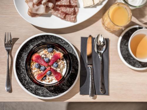 a table with a bowl of cereal with strawberries and blueberries at Aparthotel Tante Trude in Oetz