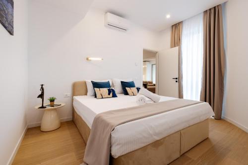 a white bedroom with a large bed with blue pillows at Central Suites in Bucharest