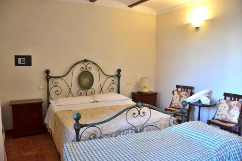 a bedroom with two beds and a lamp and a chair at Agriturismo L'Oasi della Pergola in Macchie