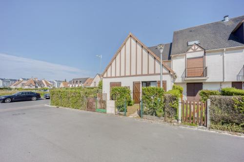 une maison avec une clôture en face d'une rue dans l'établissement Le Petit Normand - Studio avec jardin à 500 m de la plage, à Courseulles-sur-Mer