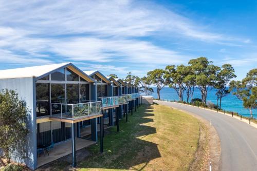 a row of houses on a road next to the ocean at Lufra Beachside Hotel in Eaglehawk Neck