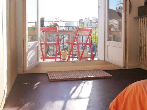 une chambre avec deux chaises rouges sur un balcon dans l'établissement Lumineux, calme, charme villageois à 2mn du métro parisien, à Malakoff