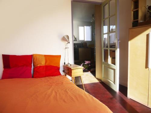 - une chambre avec un lit doté d'oreillers rouges et oranges dans l'établissement Lumineux, calme, charme villageois à 2mn du métro parisien, à Malakoff