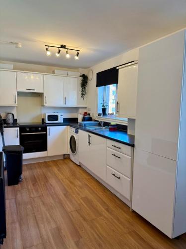 a kitchen with white cabinets and a blue counter top at 2 Bedroom Apartment near Glasgow City Centre, Celtic Park and Emirates Arena in Glasgow