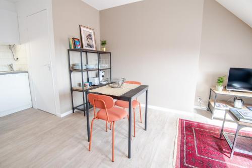 - une salle à manger avec une table et deux chaises orange dans l'établissement Le Duplex de Richelieu, à Tours