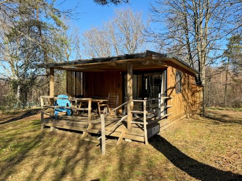 a wooden cabin with a table and chairs in the grass at Le Nouméa, 4 pers, 3 lits in Saint-Pantaléon-de-Lapleau