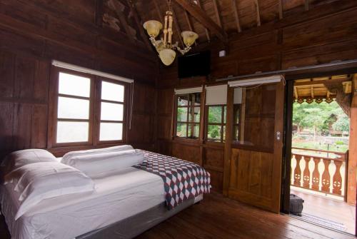 Cama en habitación con paredes y ventanas de madera en Villa Couple by Santosa Stable Resort, en Gunungpati