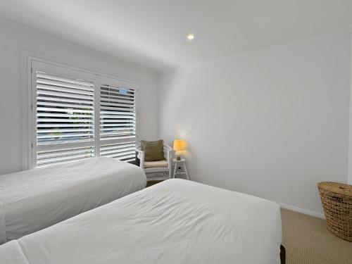 two beds in a room with a window and a chair at Serene Luxury Retreat on Malua Bay in Malua Bay