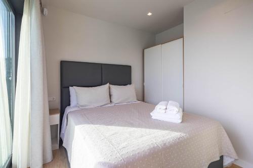 una camera da letto con un letto bianco con un asciugamano sopra di Bungalow 1 con piscina en la playa a A Pobra do Caramiñal