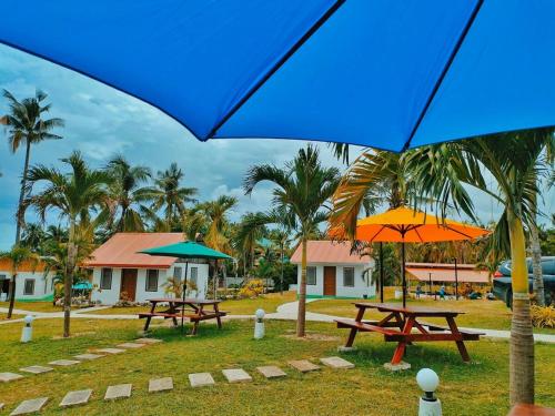 two picnic tables with umbrellas in a park at Galaxy Family Room in Dalaguete