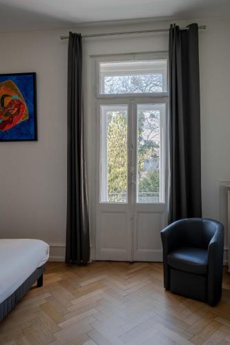 a bedroom with a bed and a chair and a door at La Résidence de l'Orangerie in Strasbourg