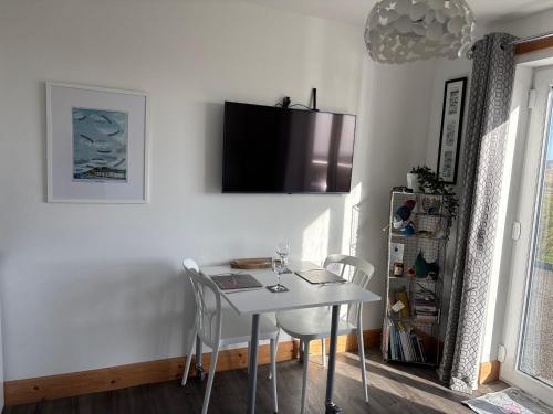 a white dining room with a white table and chairs at The Fisherman's Snug self catering North Uist in Paible
