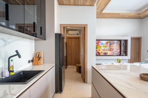 a kitchen with white counters and a sink and a tv at Mouana Breeze Mai Khao VIP 4-bedroom Pool Villa 9911 in Phuket
