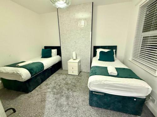 a bedroom with two beds and a mirror at Cozy Haven near Glenfield & LRI Hospitals in Leicester
