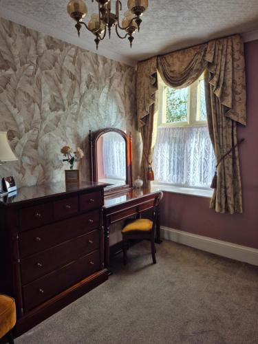 a room with a dresser and a mirror and a window at St David's Guesthouse in Haverfordwest