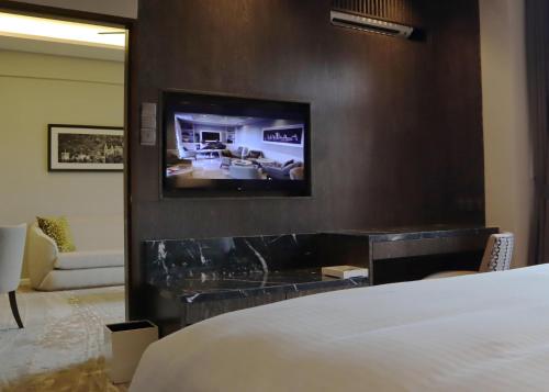a hotel room with a bed and a tv on a wall at The Chateau Spa & Wellness Resort in Bukit Tinggi