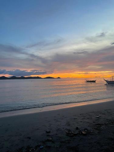 two boats sitting on the beach at sunset at Secluded 4BD Beach Villa, Fast Wifi, Pet Friendly in Lian