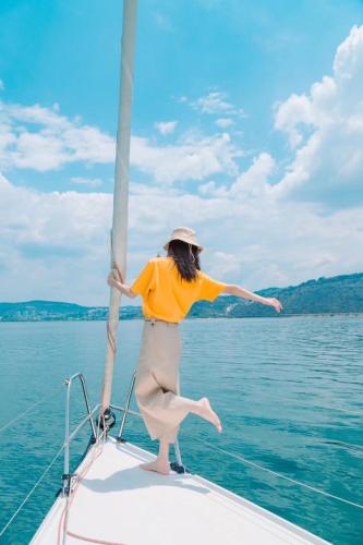 a woman standing on a boat in the water at Fuxian Lake Three Thousand French Manor Hotel in Xujiadu