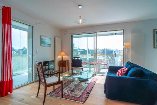 un salon avec un canapé bleu et une table en verre dans l'établissement Les Flots de la Marle - Avec parking couvert, à Vannes