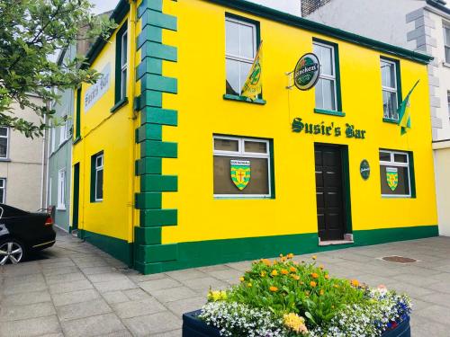 a yellow and green building with flowers in front of it at Eagles Nest Oceanview Hideaway in Drumaville