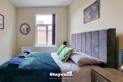 a bedroom with a bed with a blue comforter and a window at Clarence Co-living - Private Room Self-cater in Manchester